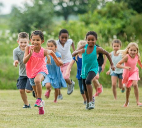 一群孩子笑着跑在外面玩捉人游戏。